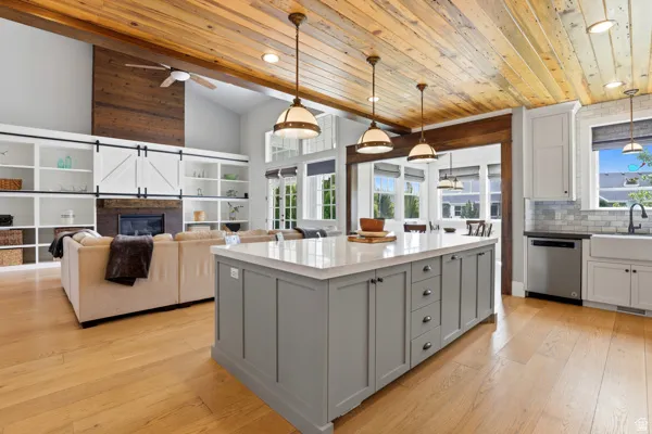 Kitchen with two tone cabinets, a center island, light wood finished floors, light stone countertops, and dishwasher