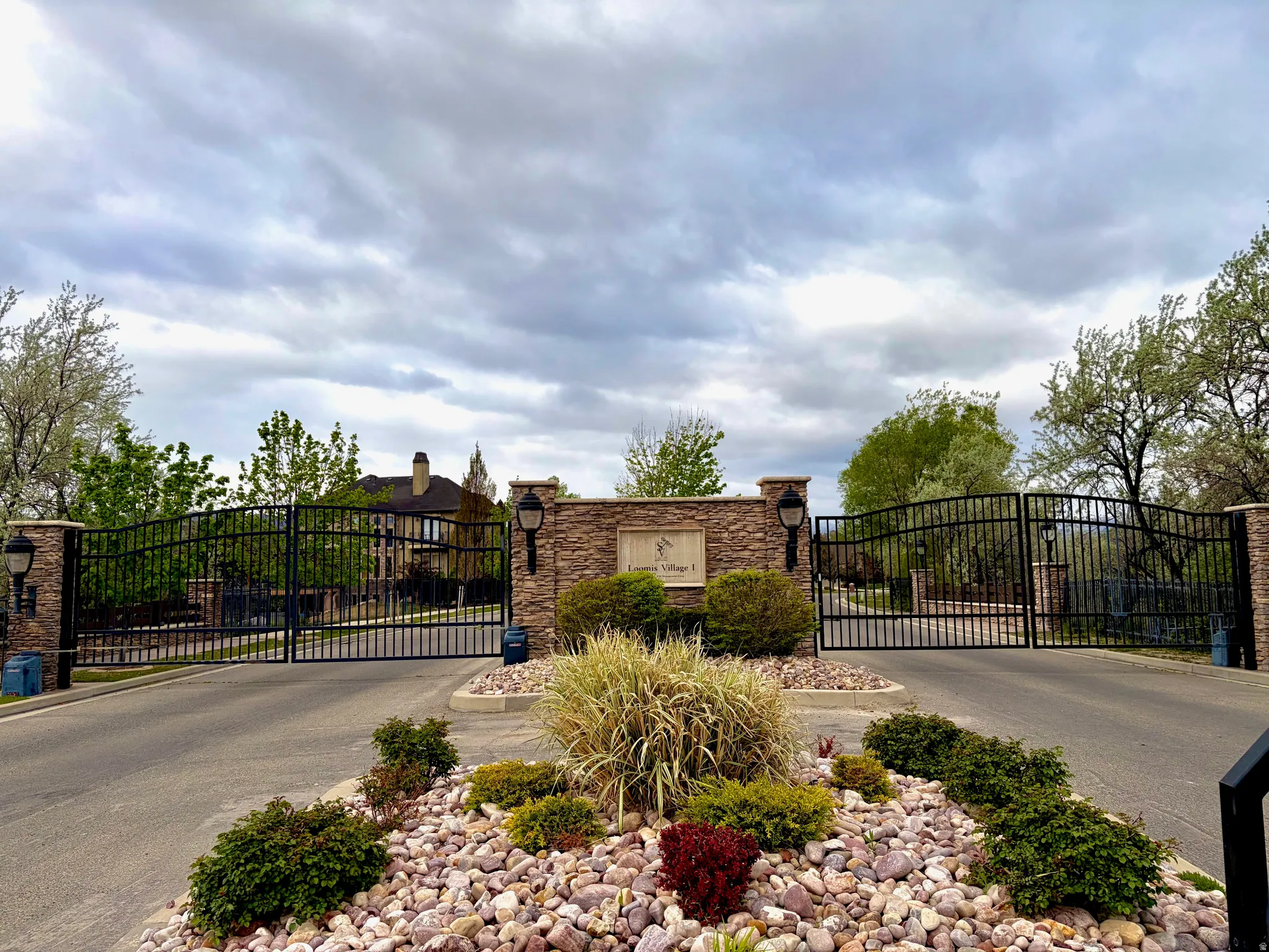 Community sign featuring a gate and asphalt driveway