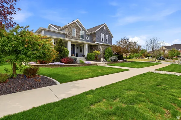 View of front of house with stone siding, covered porch, and a front yard