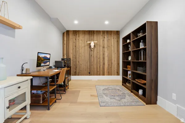 Office area featuring wood walls, light wood-style floors, an accent wall, and recessed lighting