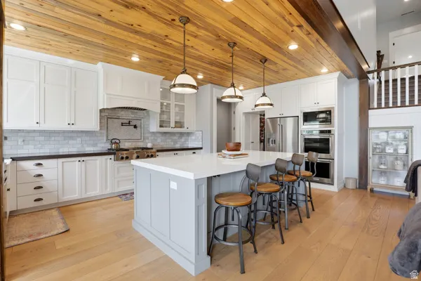 Dual tone kitchen with light wood-style floors, a large island, a kitchen bar, stainless steel appliances, and dual tone cabinetry