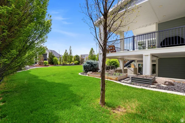 View of green lawn featuring a patio area and a vegetable garden