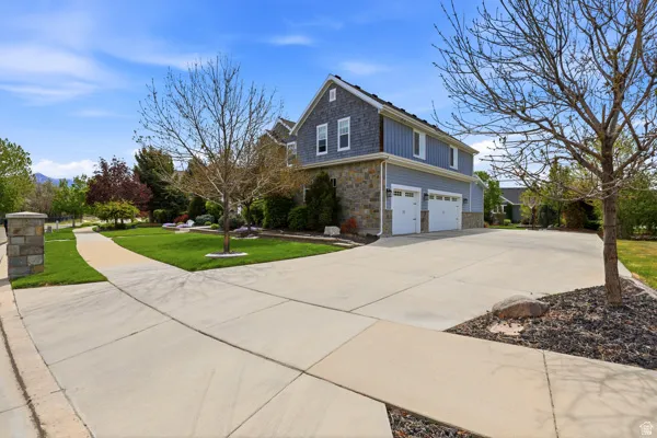 View of home's exterior featuring a lawn, a garage, stone siding, and driveway