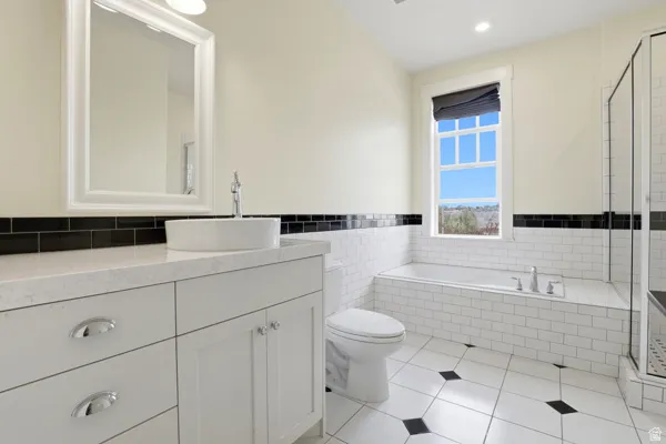 Bathroom with a shower stall, a garden tub, light tile patterned floors, vanity, and tile walls