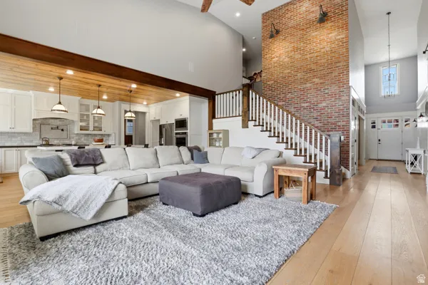 Living room with a high ceiling, light wood finished floors, a ceiling fan, and recessed lighting