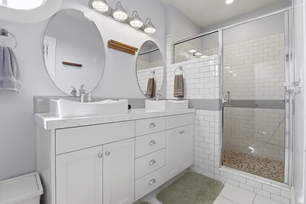 Bathroom with double vanity, a shower stall, and recessed lighting