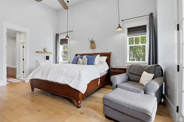 Bedroom with light wood finished floors, a ceiling fan, and connected bathroom