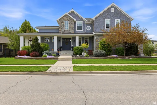 View of front of house with a front yard, covered porch, and stone siding