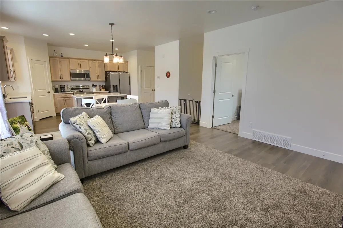 Living room featuring hanging lights and dark wood-style flooring