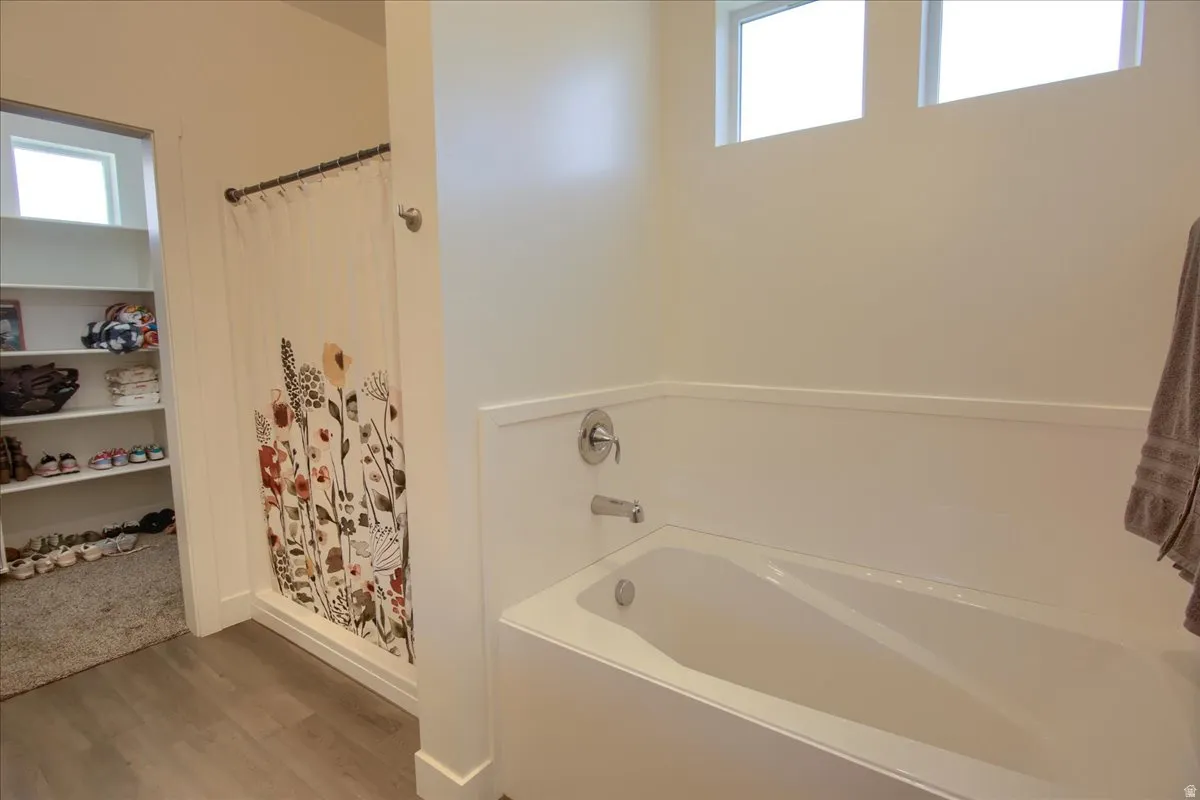 Full bath with plenty of natural light, a stall shower, a garden tub, and light wood-style flooring