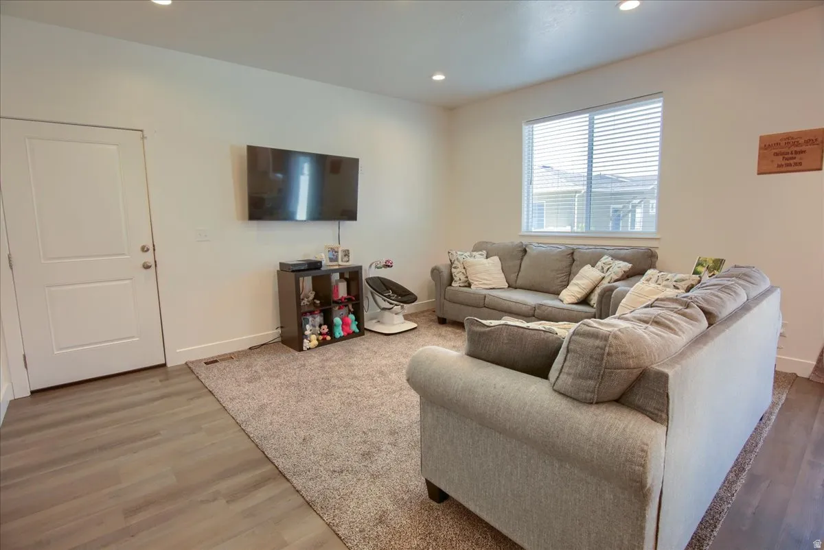 Living area with light wood-type flooring and recessed lighting