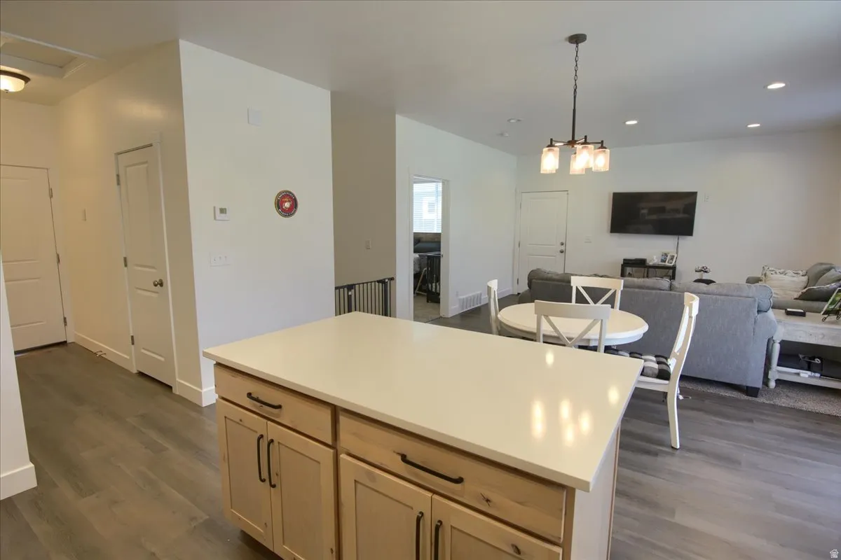 Kitchen featuring open floor plan, light countertops, dark wood finished floors, a center island, and light wood finish cabinetry