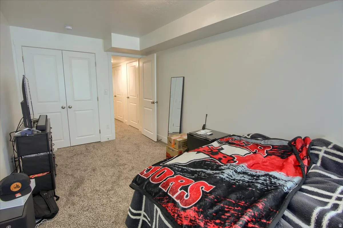 Bedroom with light carpet and a closet