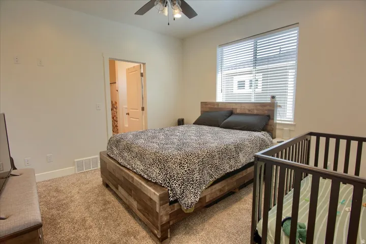 Carpeted bedroom featuring ensuite bath and a ceiling fan