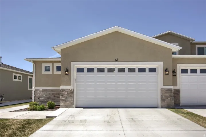 View of front of house featuring stone siding, an attached garage, and driveway