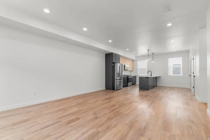 Kitchen with open floor plan, light wood finished floors, stainless steel appliances, and light countertops