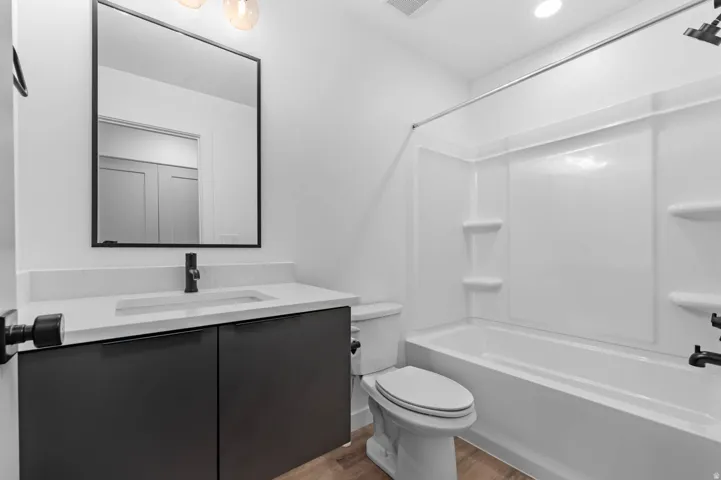 Bathroom featuring vanity, shower / bath combination, and light wood-type flooring
