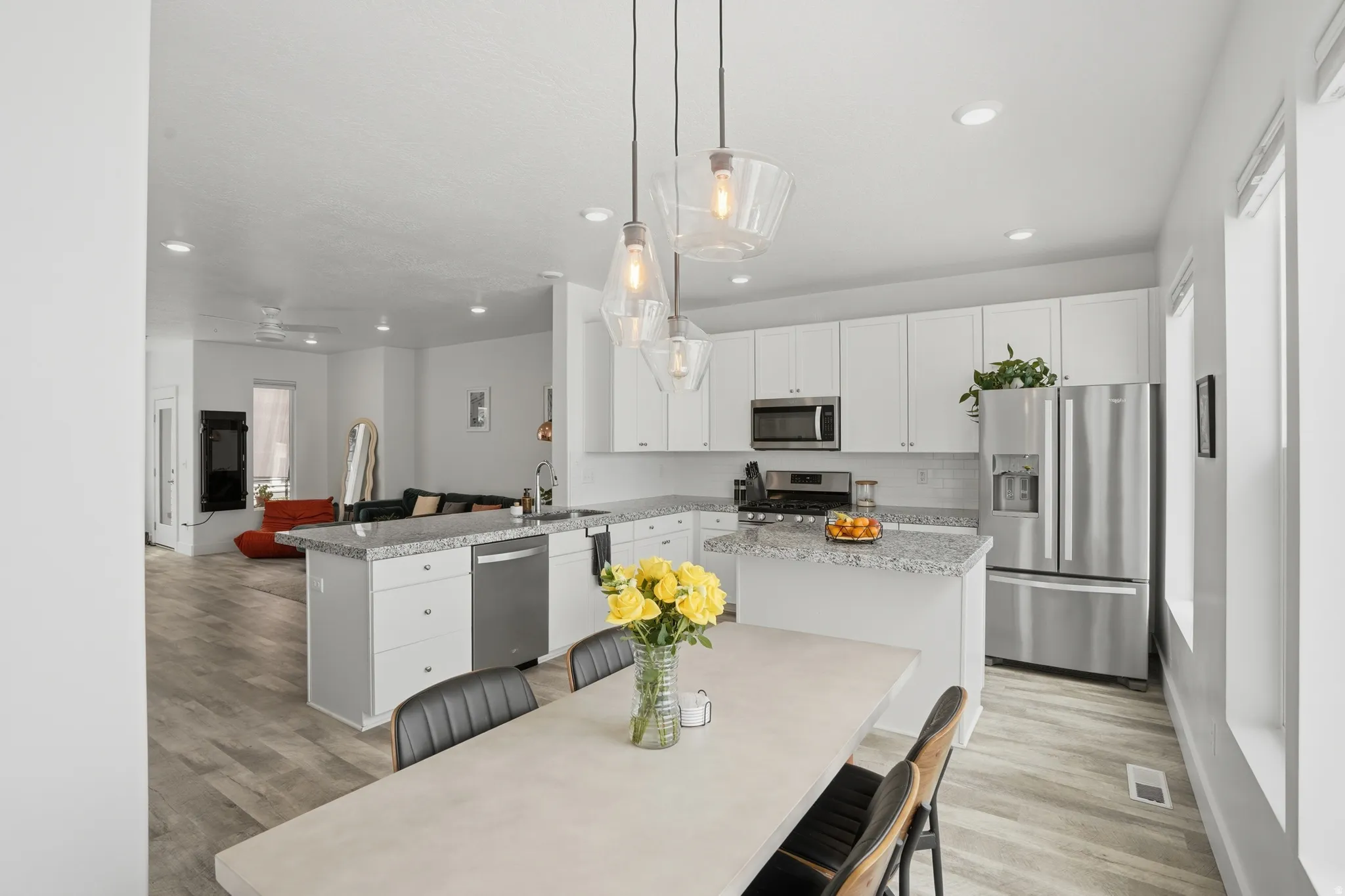 Kitchen featuring stainless steel appliances, light wood-type flooring, a peninsula, and white cabinetry