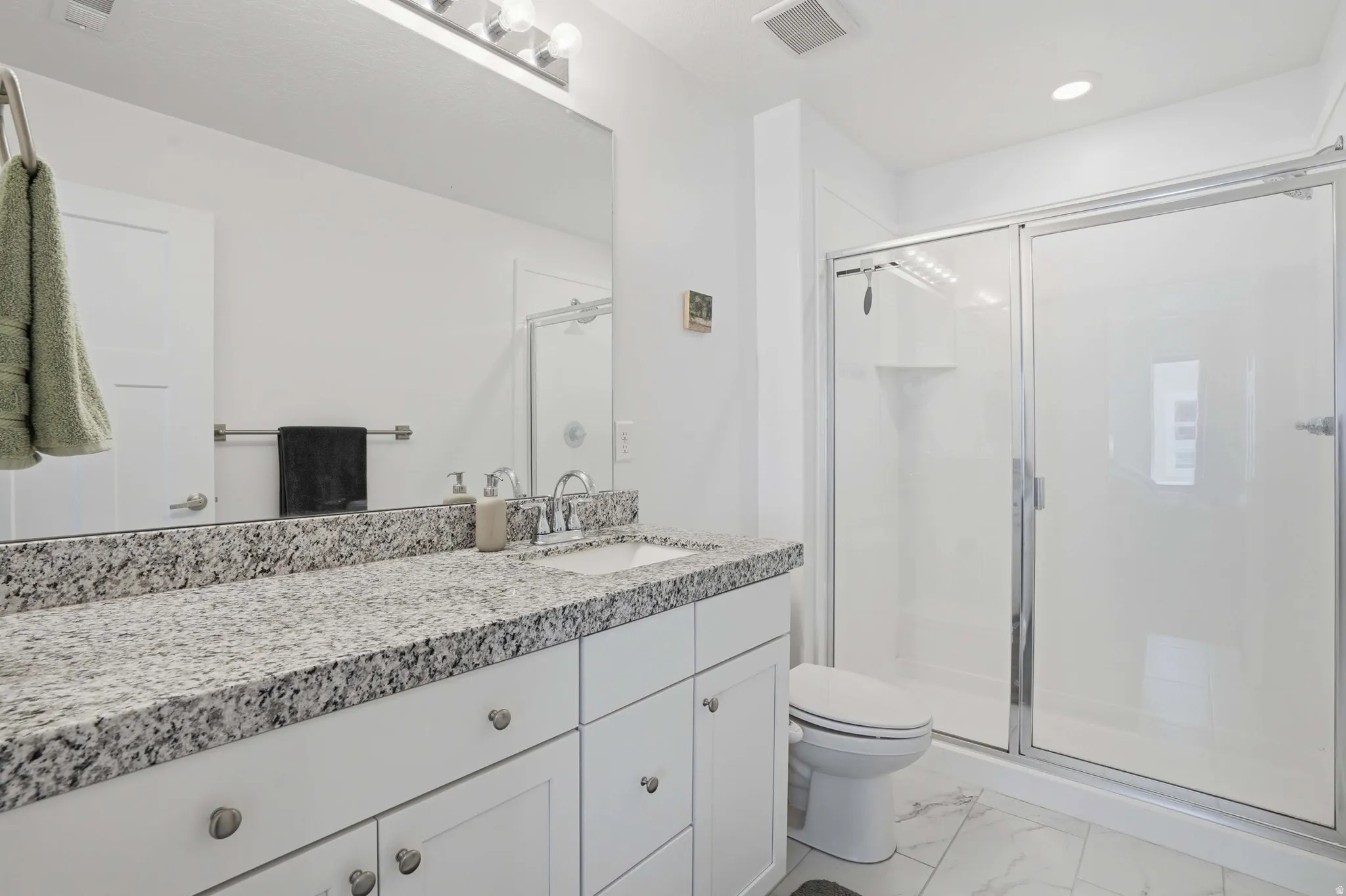 Full bathroom with a stall shower, vanity, light marble finish floors, and recessed lighting