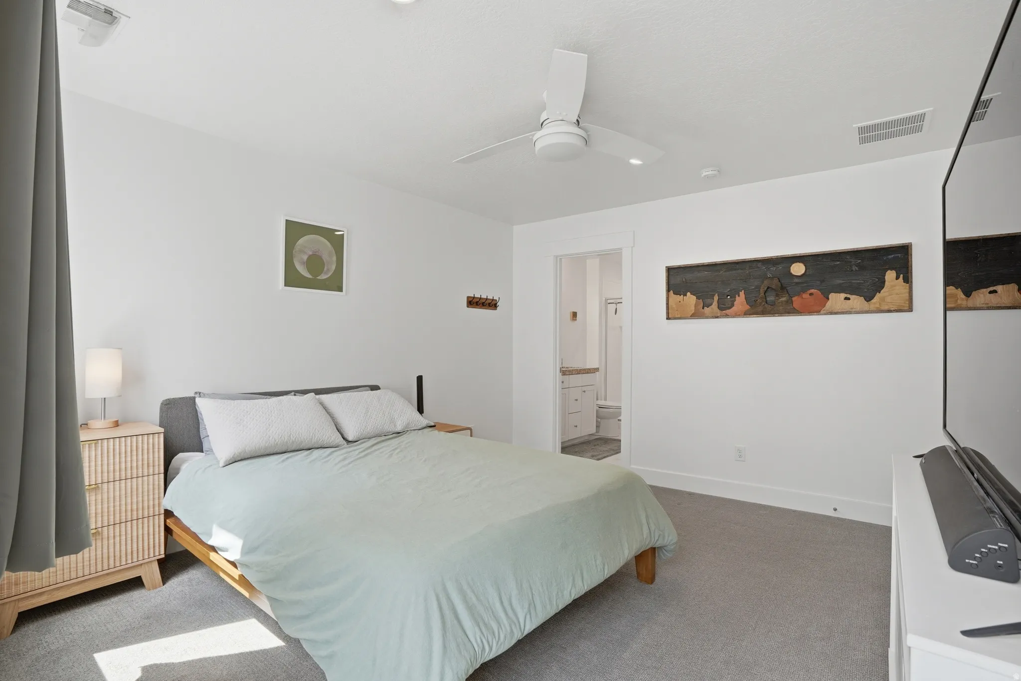 Carpeted bedroom featuring ensuite bath and a ceiling fan