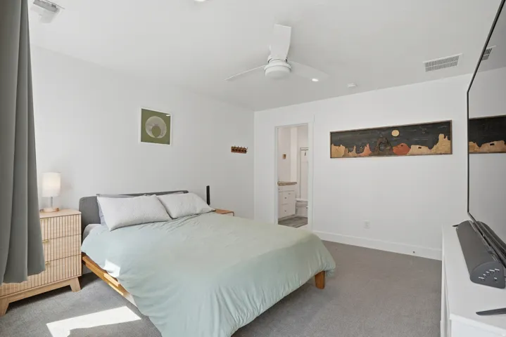 Carpeted bedroom featuring ensuite bath and a ceiling fan