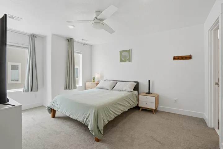 Bedroom with light colored carpet and a ceiling fan