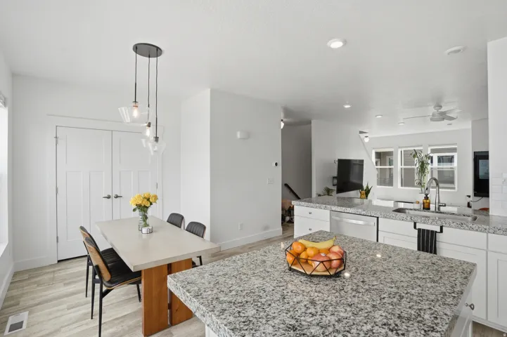 Kitchen with white cabinets, light stone counters, a peninsula, and a kitchen island