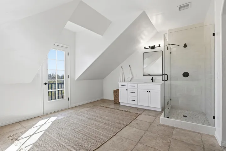 Full bathroom featuring vanity, a shower stall, lofted ceiling, and light stone finish floors
