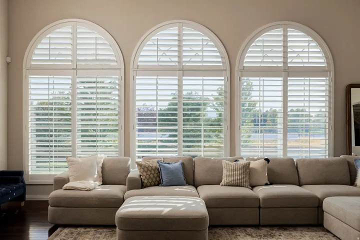 Three arched windows featuring white louvered shutters
