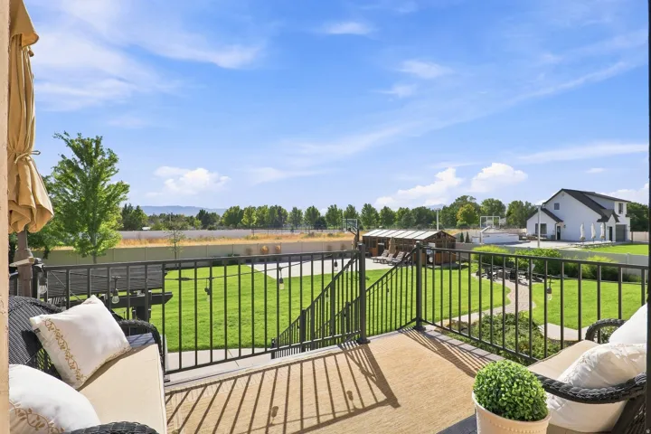 Expansive upper-level deck with black iron railings, overlooking a manicured lawn and distant scenery