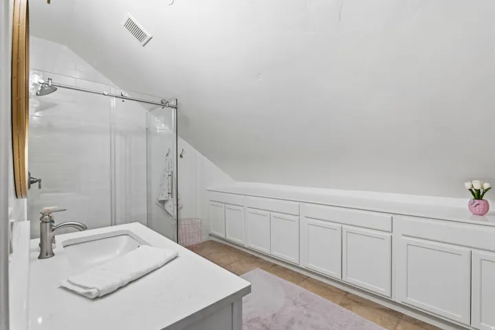 Bathroom featuring lofted ceiling, a stall shower, vanity, and light tile patterned floors