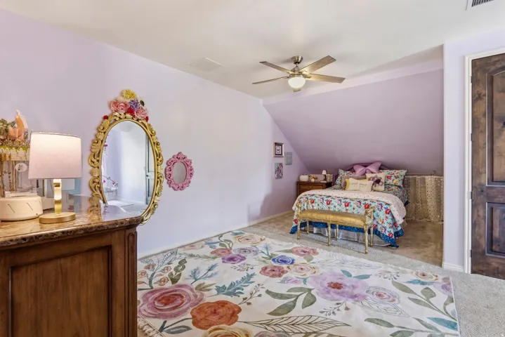 Bedroom with light colored carpet, lofted ceiling, and ceiling fan