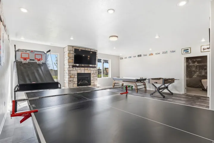 Recreation room featuring a stone fireplace and baseboards