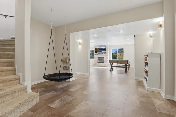 Expansive open-concept living area featuring wood-finish flooring, recessed lighting, and a stone-clad fireplace