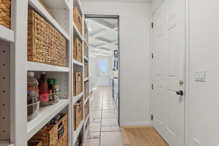 Extensive pantry featuring adjustable shelving, a paneled interior door, and tile flooring