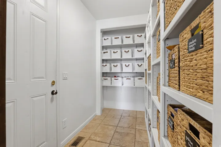 Expansive pantry featuring custom built-in shelving, organized storage solutions, and durable tile flooring
