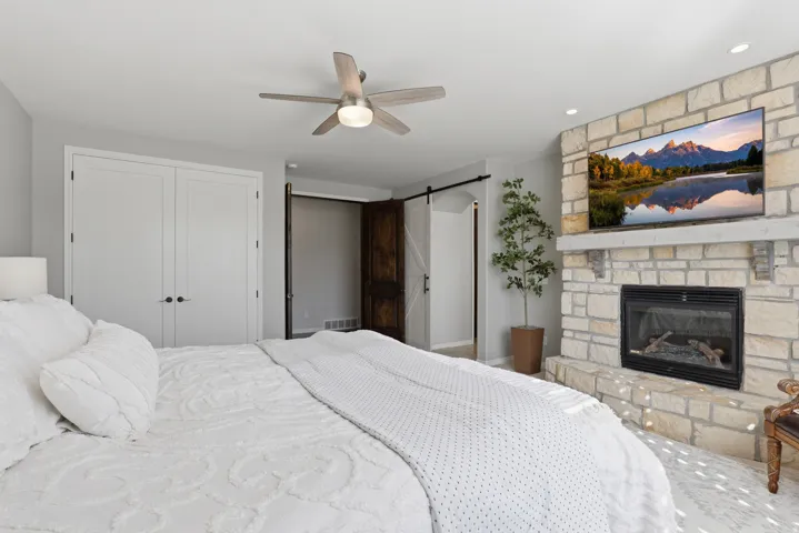 Stone-clad fireplace with mantel, built-in fireplace, and recessed lighting