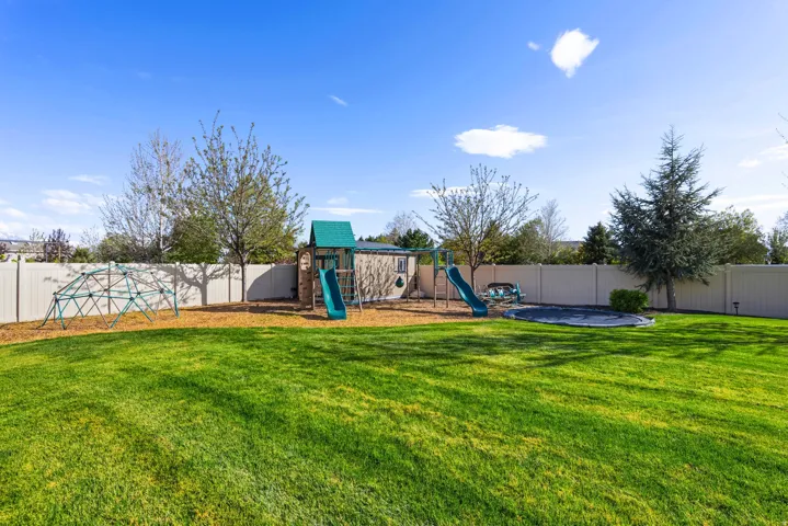 Fenced backyard featuring a playground and a patio