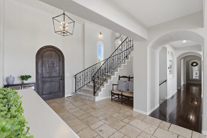 Arched entry door, tile flooring, wrought iron staircase railing, recessed lighting, and a chandelier