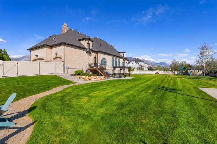 Back of property featuring a gate, a mountain view, a fenced backyard, stucco siding, and a chimney