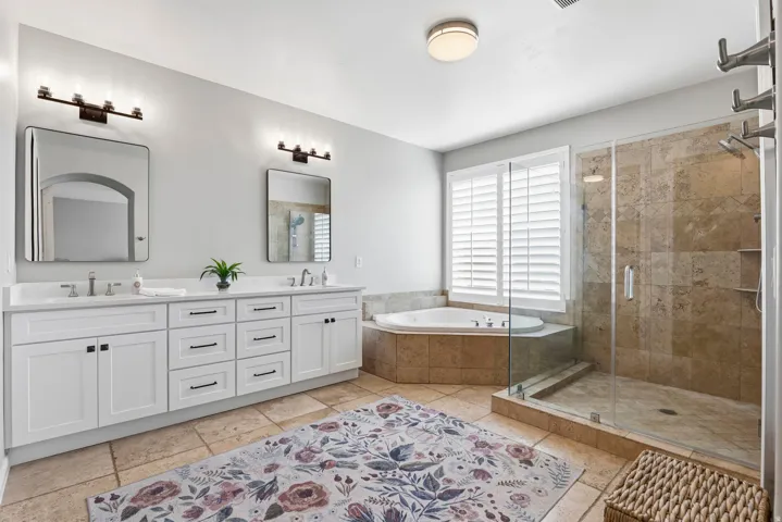 Bathroom with double vanity, a shower stall, and a bath