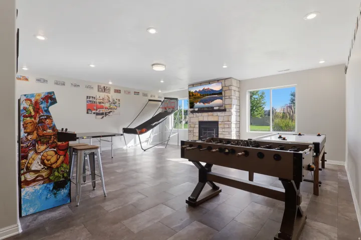 Spacious room featuring recessed lighting, a stone-faced fireplace, large windows, and tile flooring