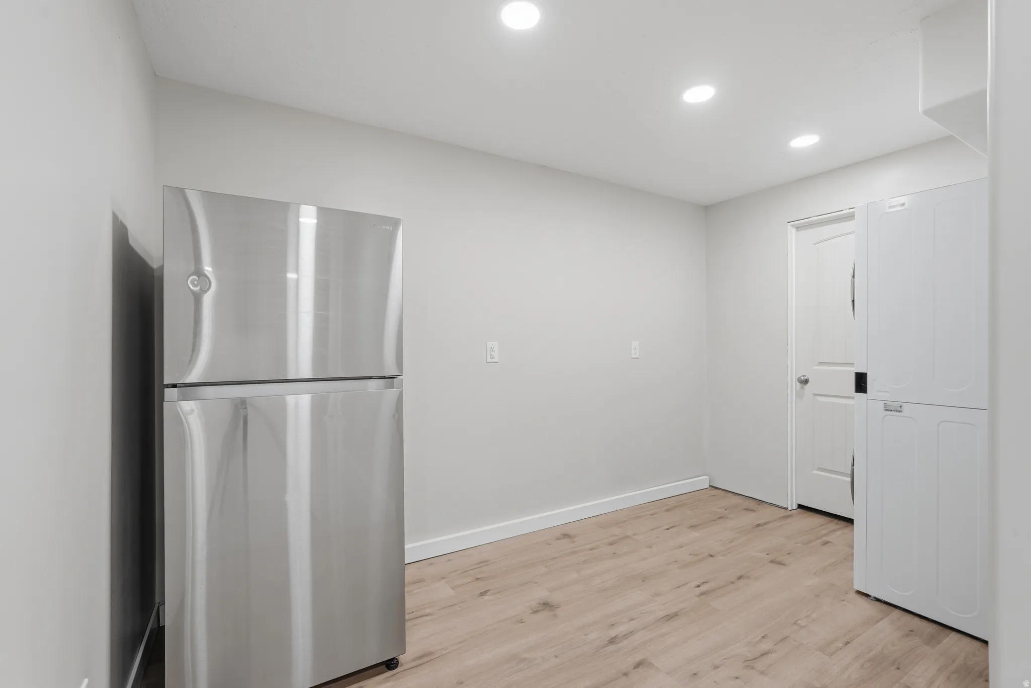freestanding refrigerator, light wood finished floors, washer / clothes dryer