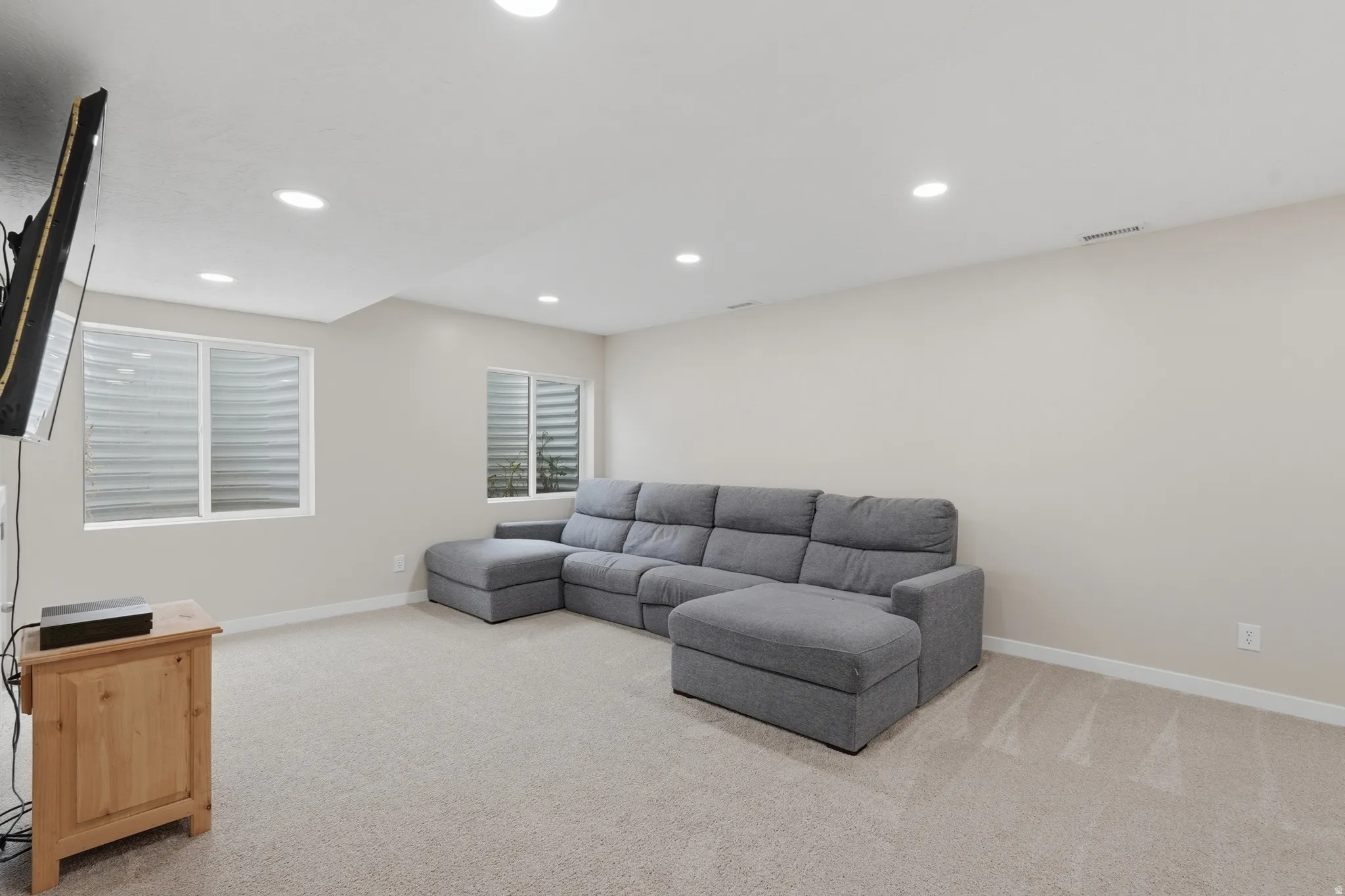 Family room with light colored carpet and recessed lighting