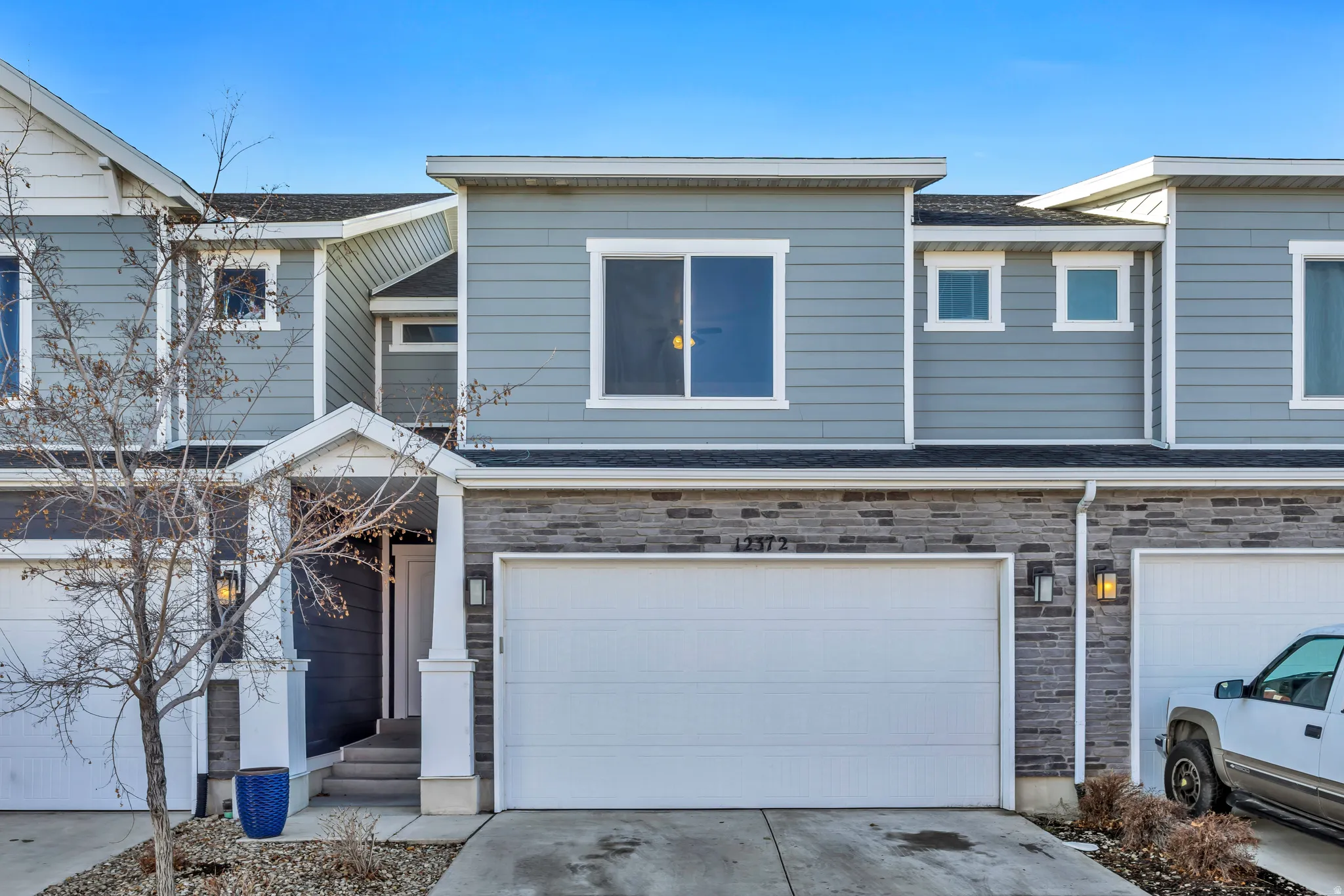 View of front facade with stone siding, concrete driveway, a garage, and a shingled roof