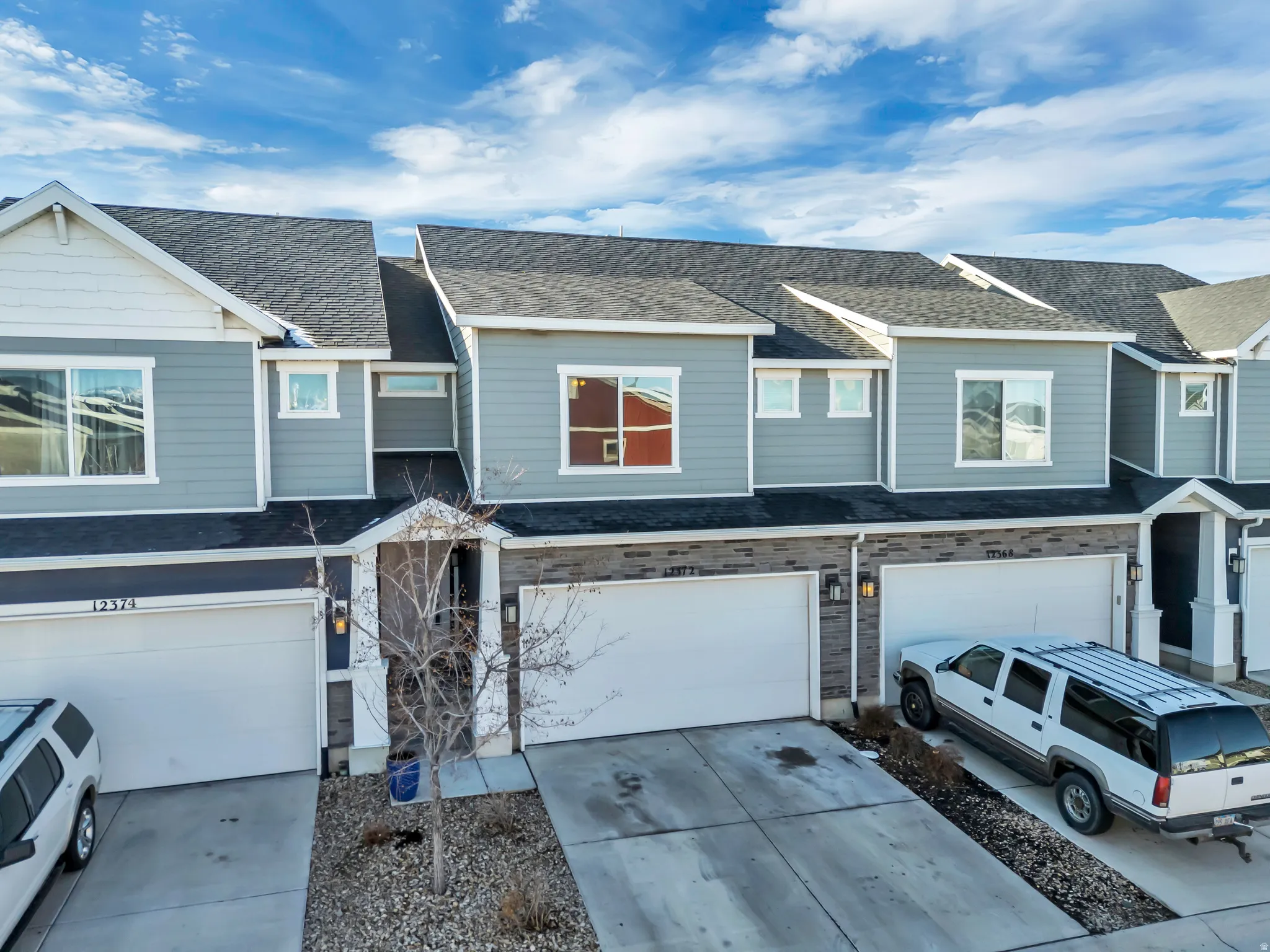 Craftsman-style home featuring roof with shingles, a residential view, an attached garage, and driveway