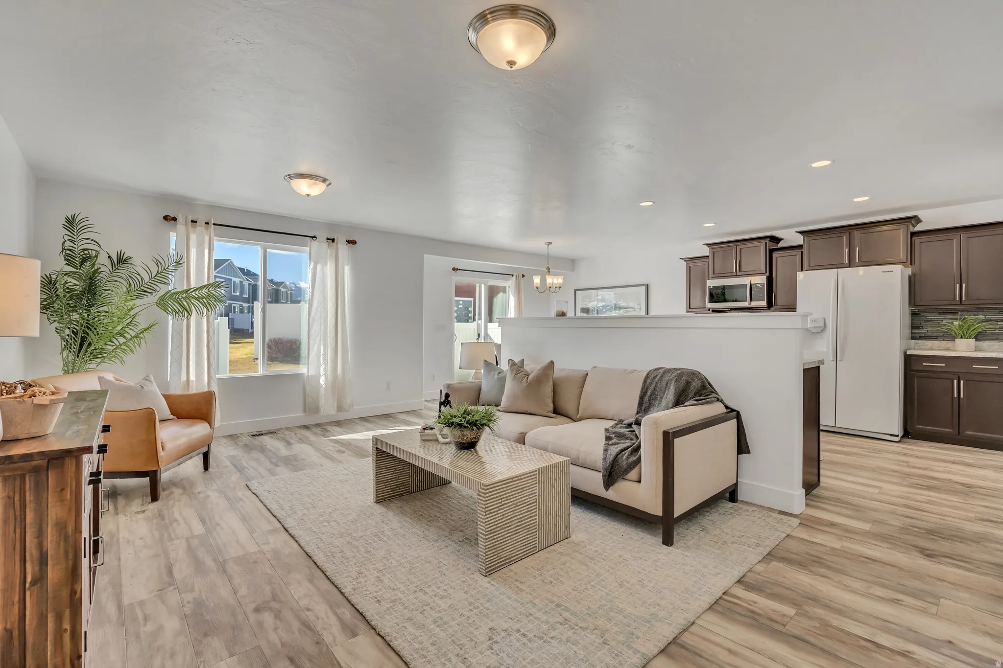 Living room featuring light wood-type flooring and suspended lighting