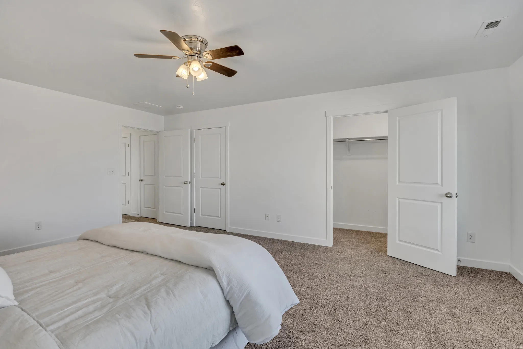 Bedroom featuring carpet floors, a walk in closet, and a ceiling fan