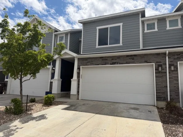 View of front facade with driveway, stone siding, and a garage
