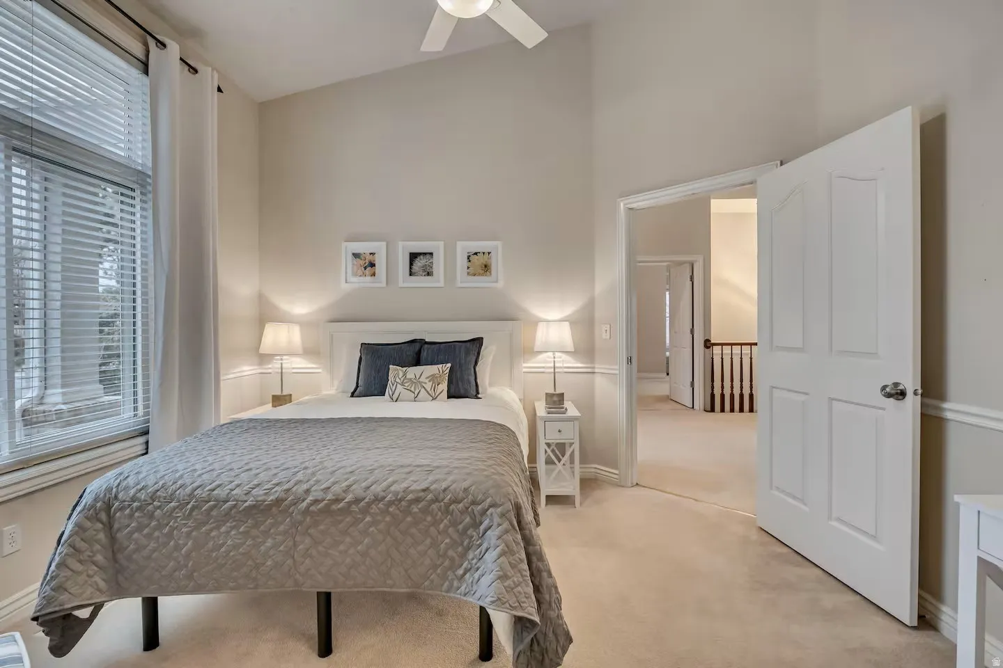 Bedroom with light colored carpet, vaulted ceiling, and a ceiling fan
